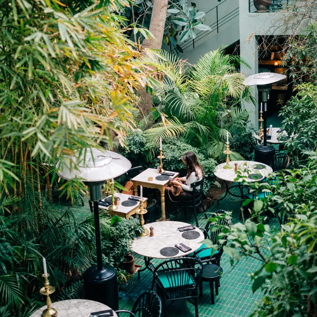 Patio du Jardin vu d'en haut, tables rondes entourées de palmiers et de bambous