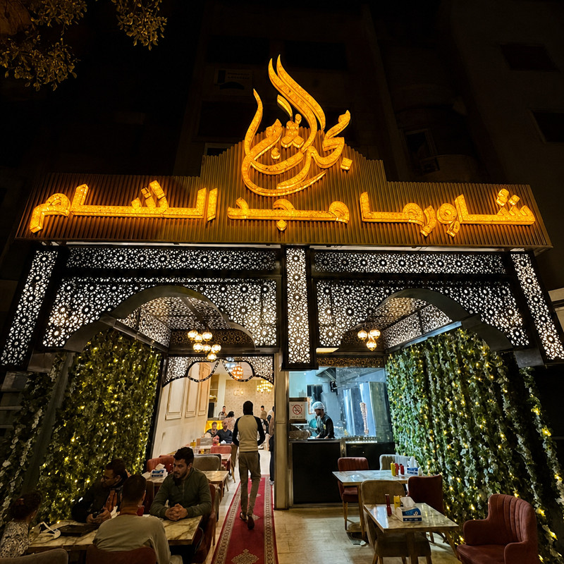 Façade illuminée de Chawarma Majd Acham à Casablanca, enseigne dorée en arabe et moucharabiehs