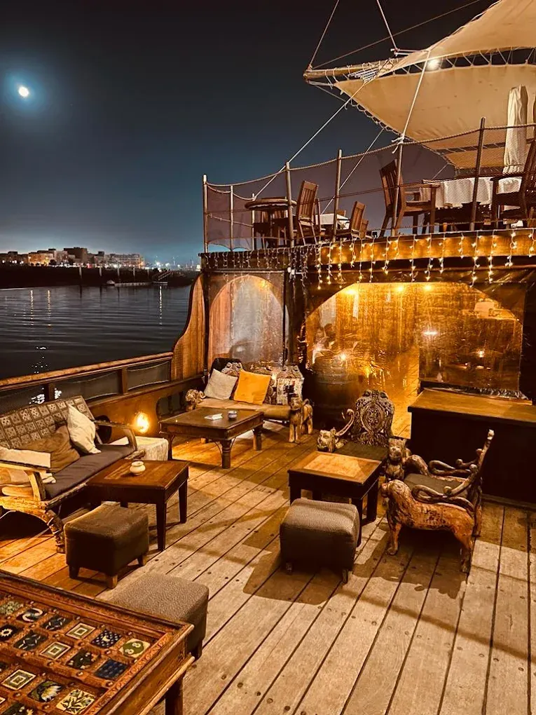 Pont du Dhow le soir, salons en bois et lanternes, avec la rive de Rabat en arrière-plan