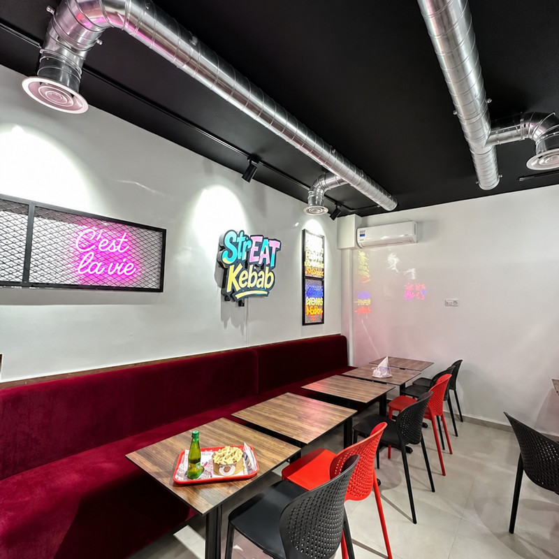 Salle de Streat Kebab, banquette bordeaux et néon « C'est la vie »