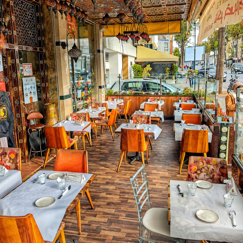 Terrasse couverte de Yamal Acham avec chaises orange et tables nappées