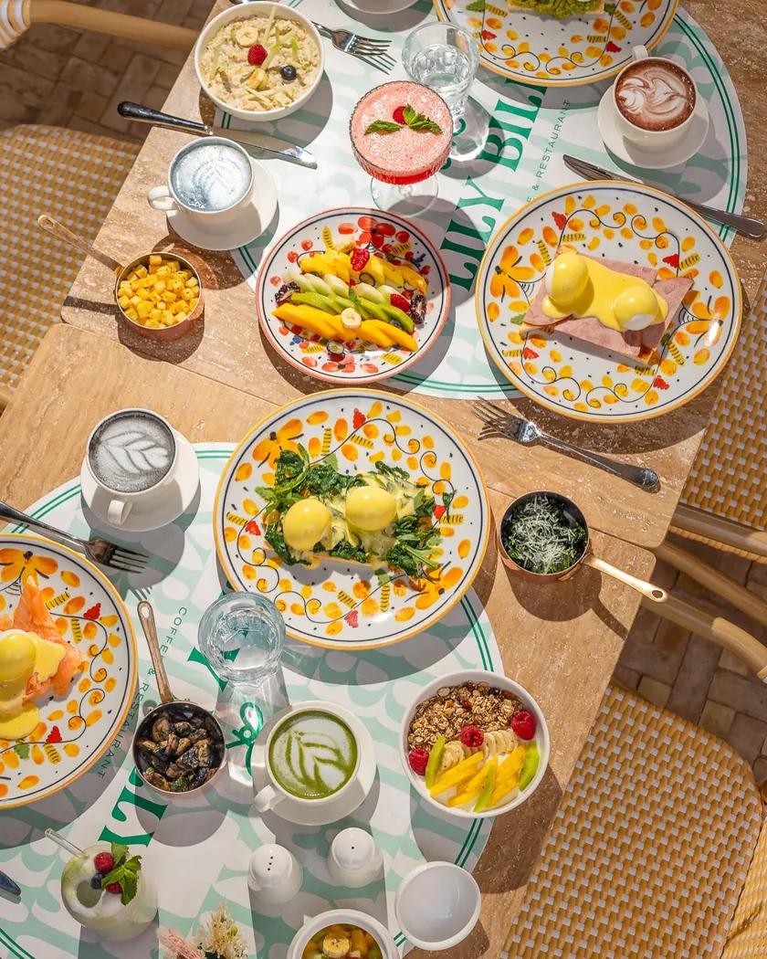 Table de brunch vue du dessus chez Lily Billy : œufs Bénédicte, fruits, bowls et boissons