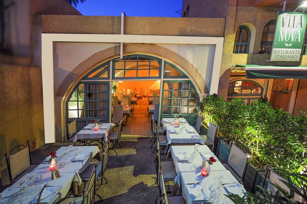 Vita Nova à Marrakech : terrasse dressée de nappes blanches devant la façade à grandes fenêtres cintrées