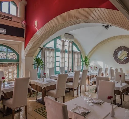 Vita Nova à Marrakech : salle sous arcades, murs rouges et chaises housées de blanc