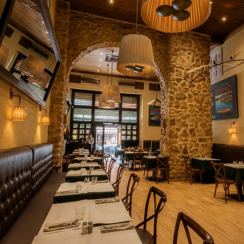 Mamma Mia à Marrakech : salle en longueur, murs de pierre apparente, arche et banquettes de cuir