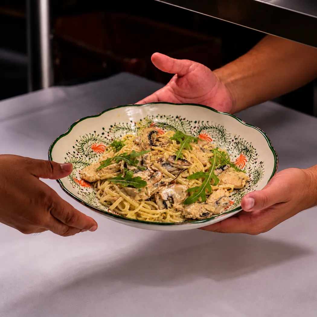 Papàlazzo à Marrakech : assiette de spaghetti aux champignons et roquette présentée à deux mains