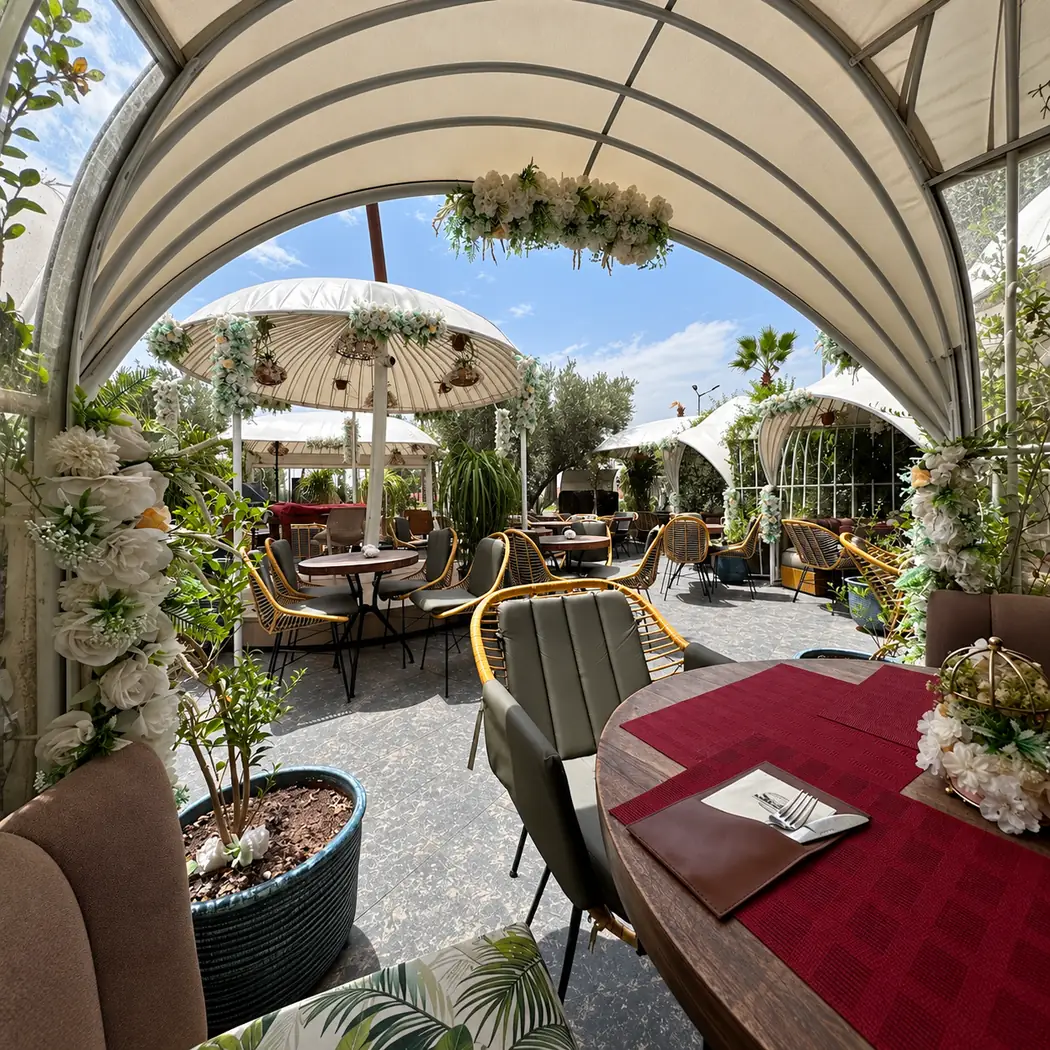 Terrasse d'Americana Brunch & Cake à M Avenue, sous une verrière, avec parasols et plantes