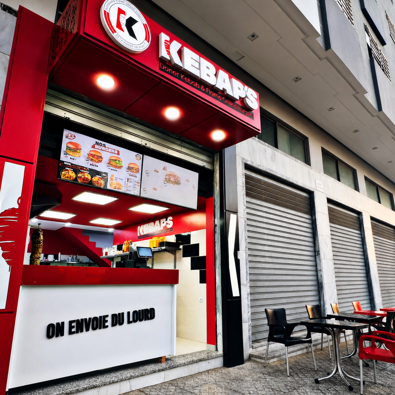 Devanture rouge et blanche de Kebap's avec son comptoir et quelques tables dehors