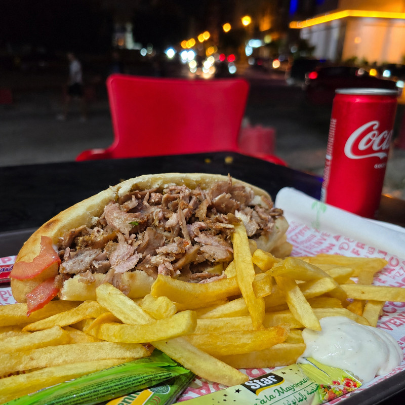 Sandwich kebab garni, frites et canette sur une table en terrasse le soir chez Kebap's