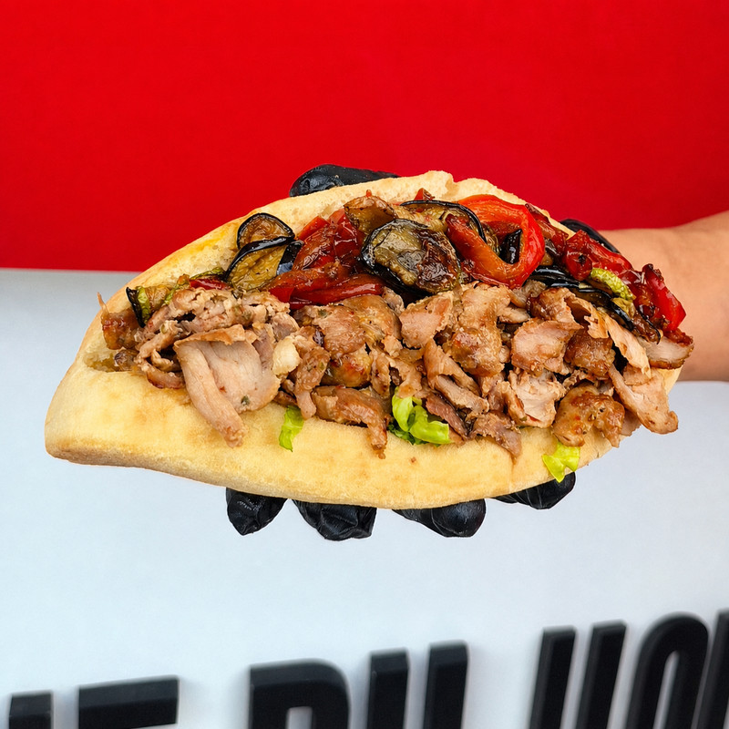 Pain kebab garni de viande et de légumes grillés tenu en main chez Kebap's