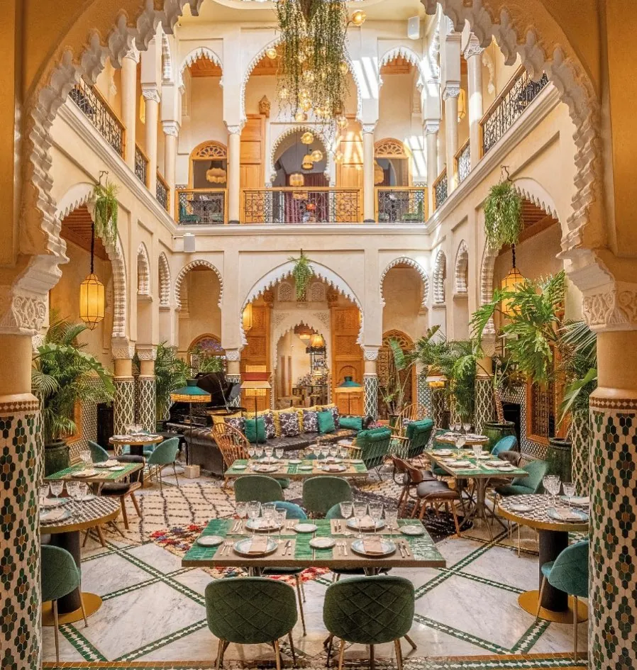 Patio de Dar Dada à Casablanca sur deux niveaux : arcades sculptées, plantes et tables dressées