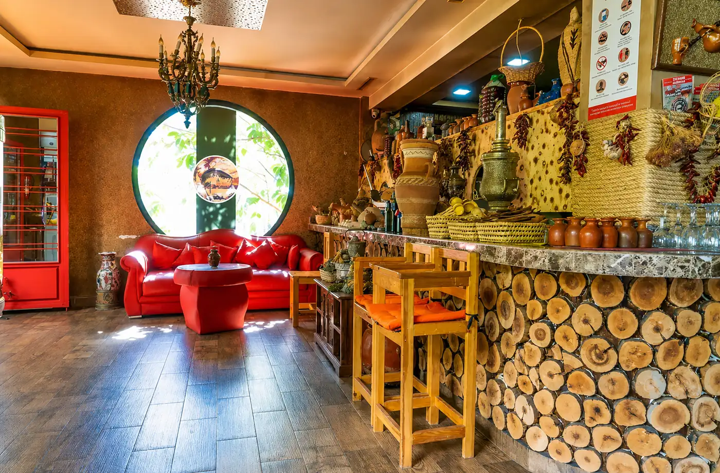 Coin salon de Villa Al Achab avec fauteuils rouges, hublot et comptoir en rondins