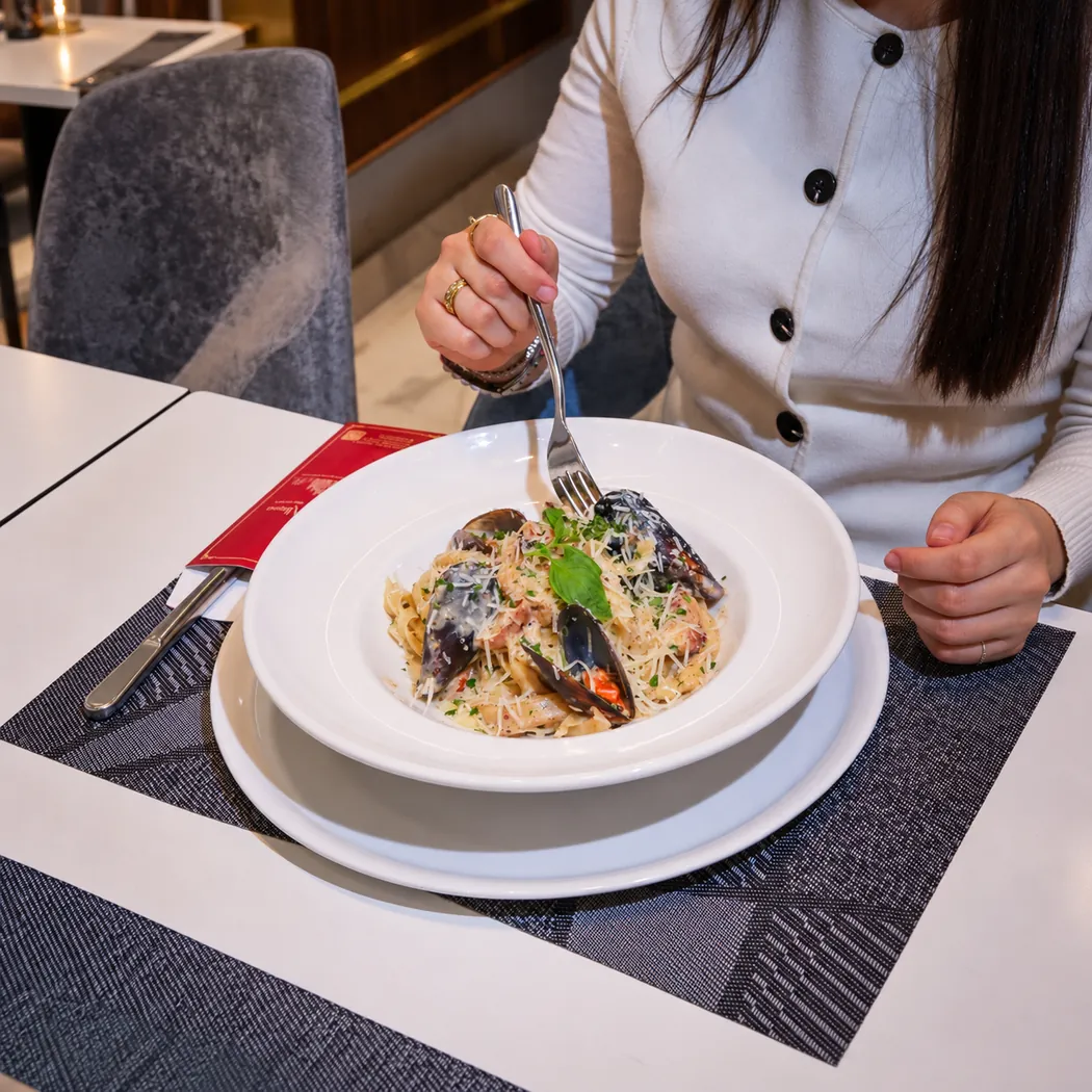 Assiette de pâtes aux moules servie à table chez Gran Milano