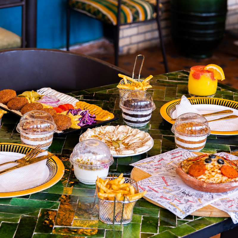 Table en zellige vert chez Iraki Shawarma : falafels, houmous, frites et pizza