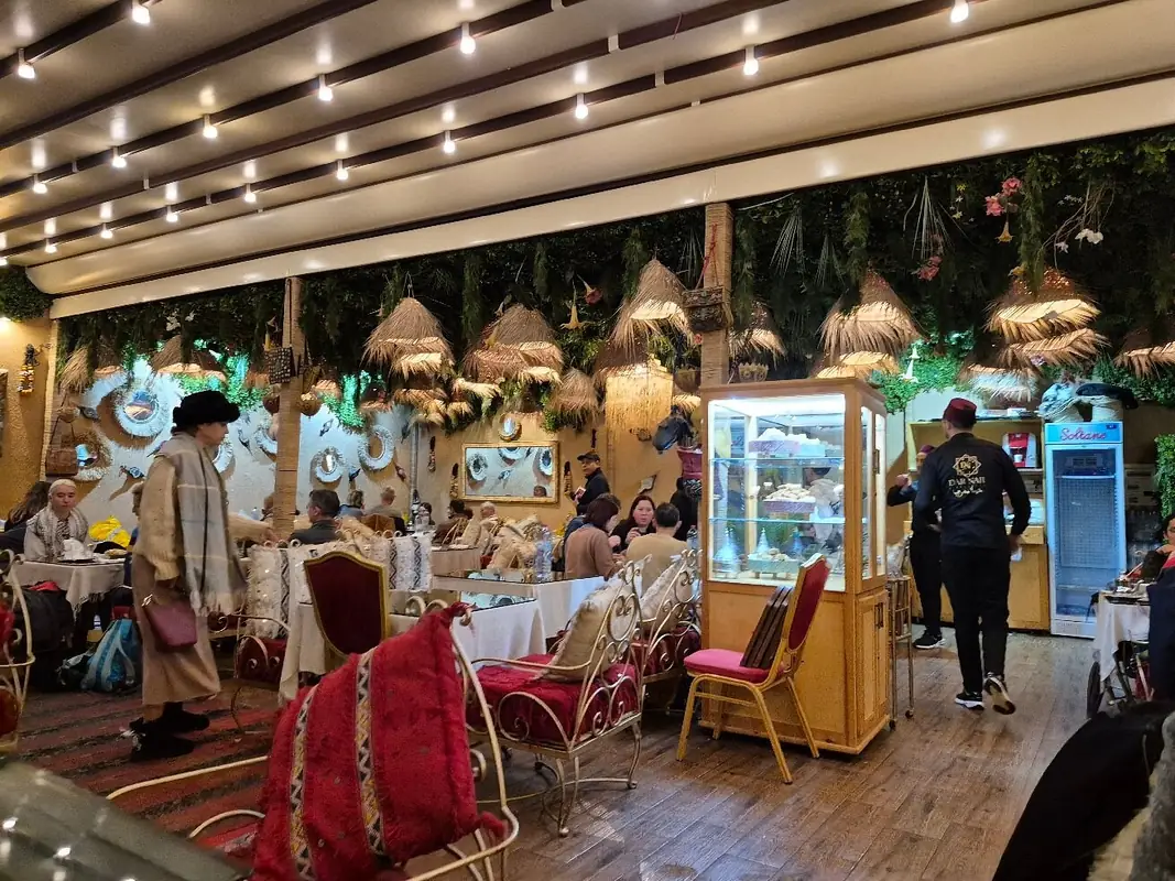 Salle animée de Dar Naji à Rabat sous des suspensions en palmier et une guirlande de lumières