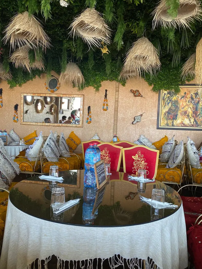 Table ronde nappée et fauteuils rouges dans un salon décoré de Dar Naji