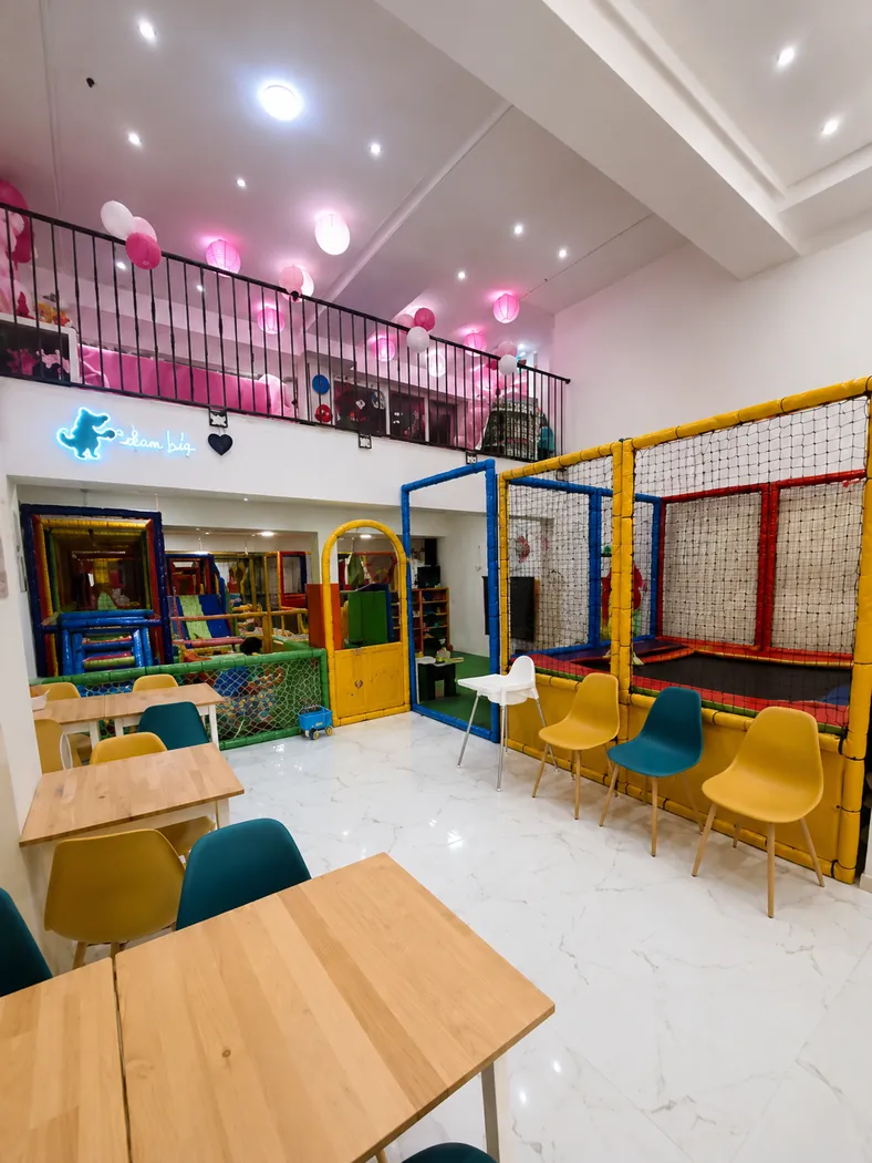 Espace café aux tables en bois et mezzanine de Totem Kids Coffee