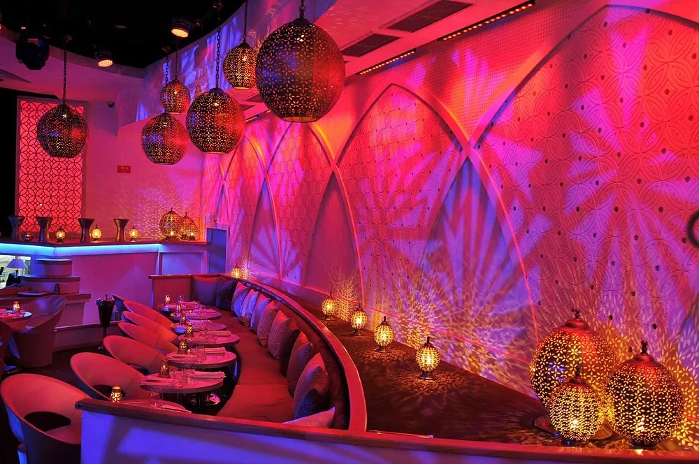 Banquette courbe du So Lounge Marrakech sous des lanternes ajourées et des lumières roses