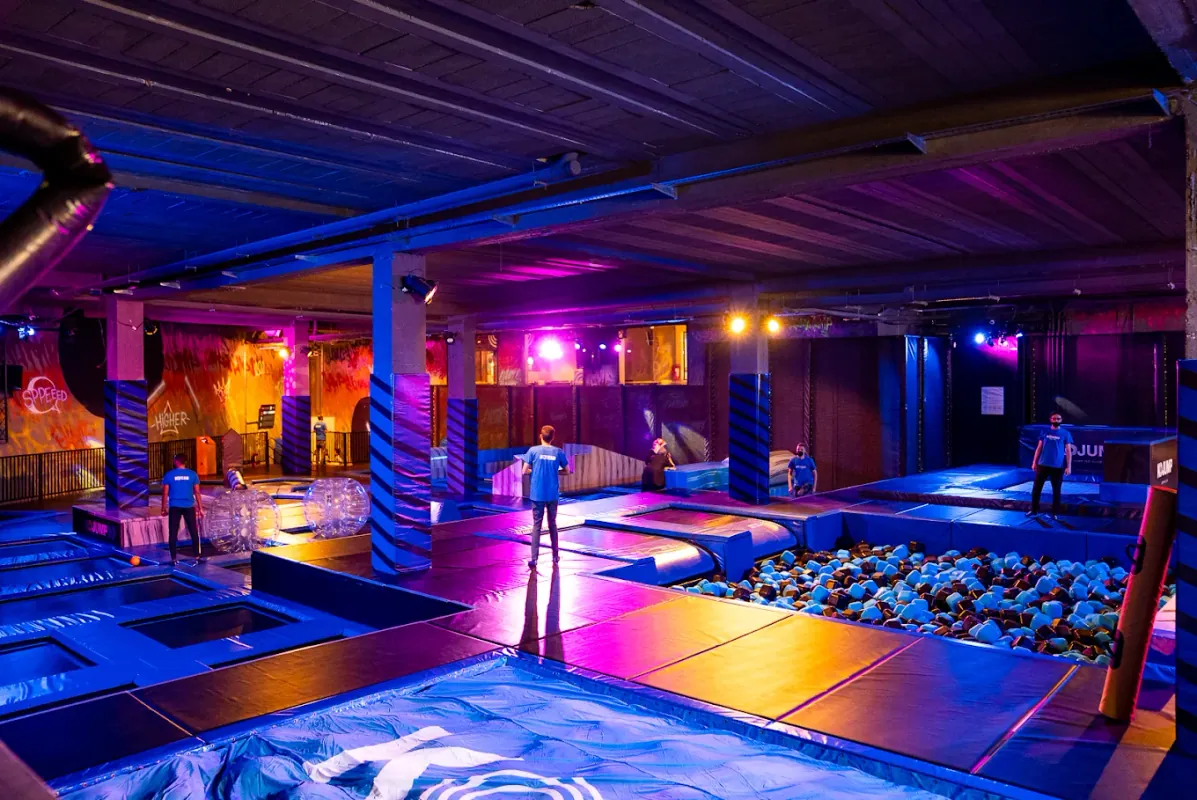 Vue d'ensemble d'un parc Kojump : trampolines, piscine à mousses et éclairage néon