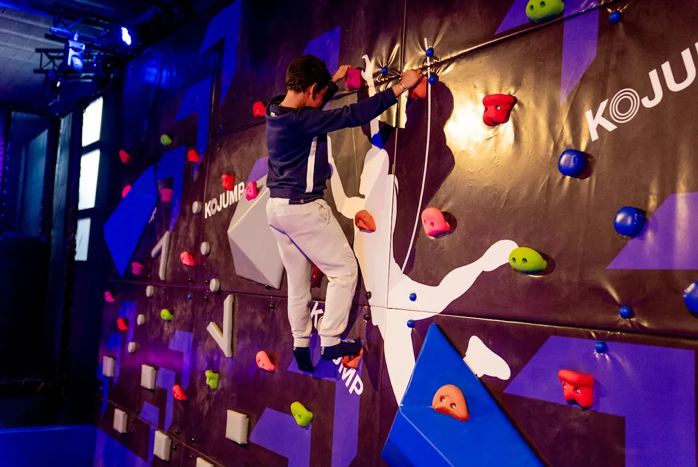 Enfant sur un mur d'escalade aux prises colorées chez Kojump