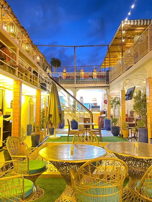 Terrasse du Rooftop El Kennaria le soir, fauteuils en rotin et guirlandes lumineuses