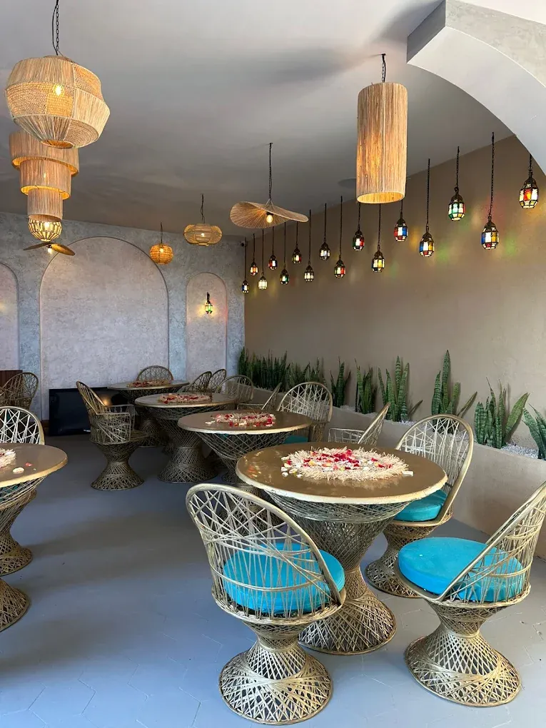 Salle du Rooftop El Kennaria, tables rondes et suspensions en osier