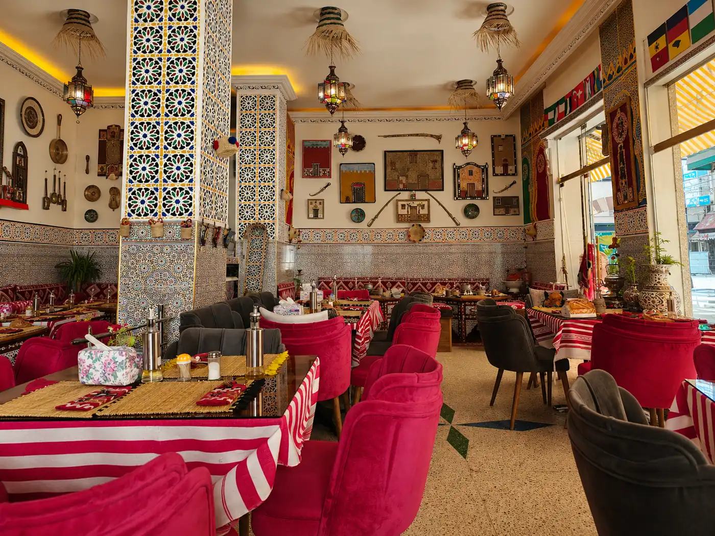 Salle du restaurant Cheikh Ibrahim à Tanger : piliers en zellige, lanternes et fauteuils rouges