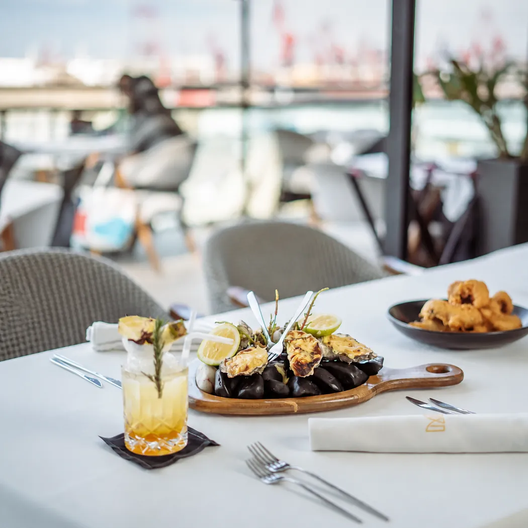 Table dressée près des baies vitrées de Mood's, avec vue sur le port de la Marina