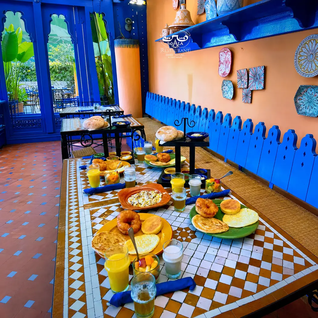 Salle bleue de La Sqala à Casablanca : tables en zellige dressées pour le petit-déjeuner, ouvertes sur le jardin