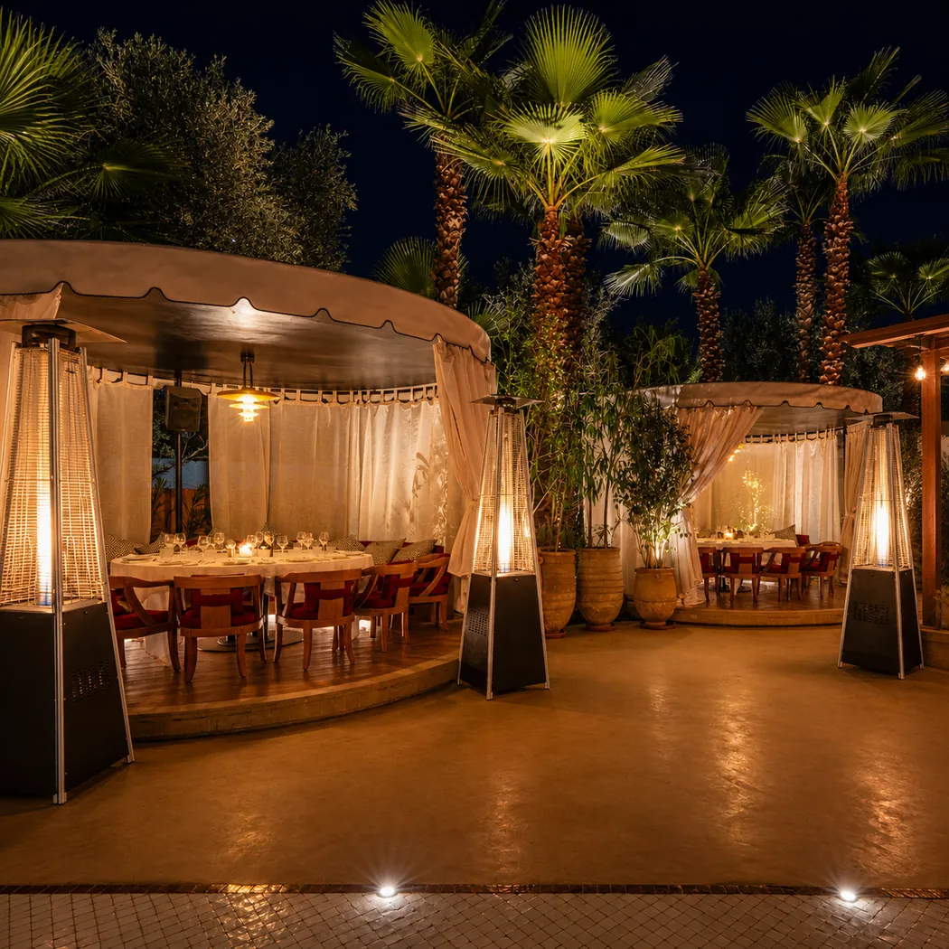 Noto à Marrakech : jardin de nuit sous les palmiers, alcôves à rideaux blancs et tables dressées