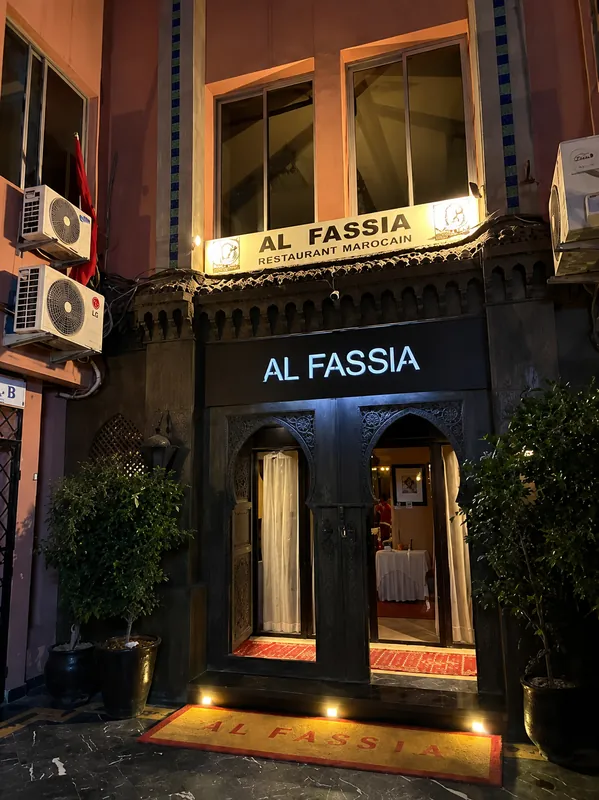 Entrée d'Al Fassia de nuit, enseigne lumineuse et tapis rouge devant la porte