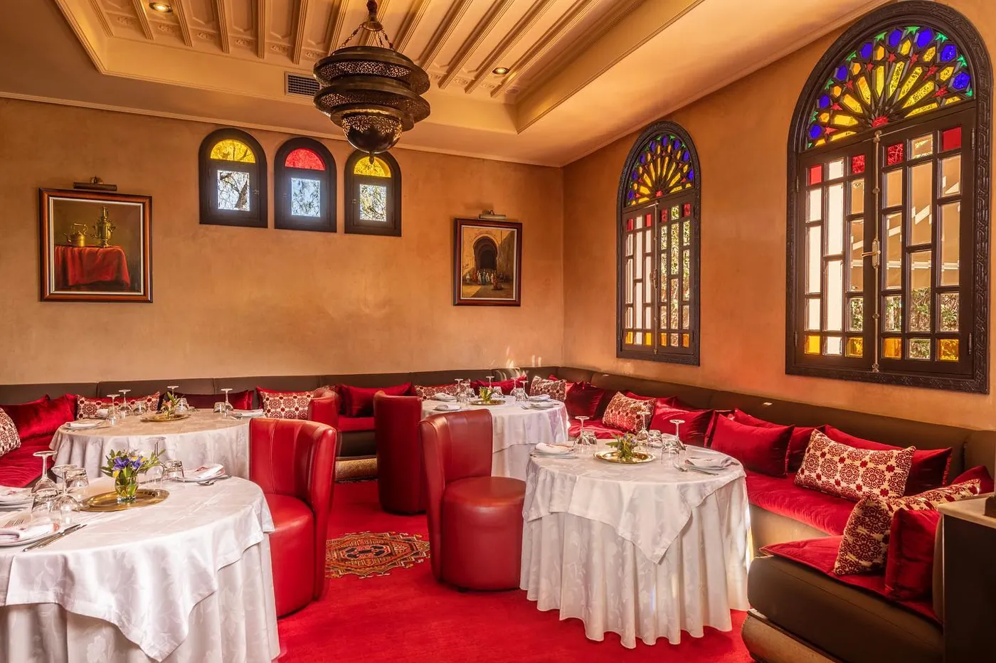 Salle d'Al Fassia : banquettes rouges, nappes blanches et vitraux colorés