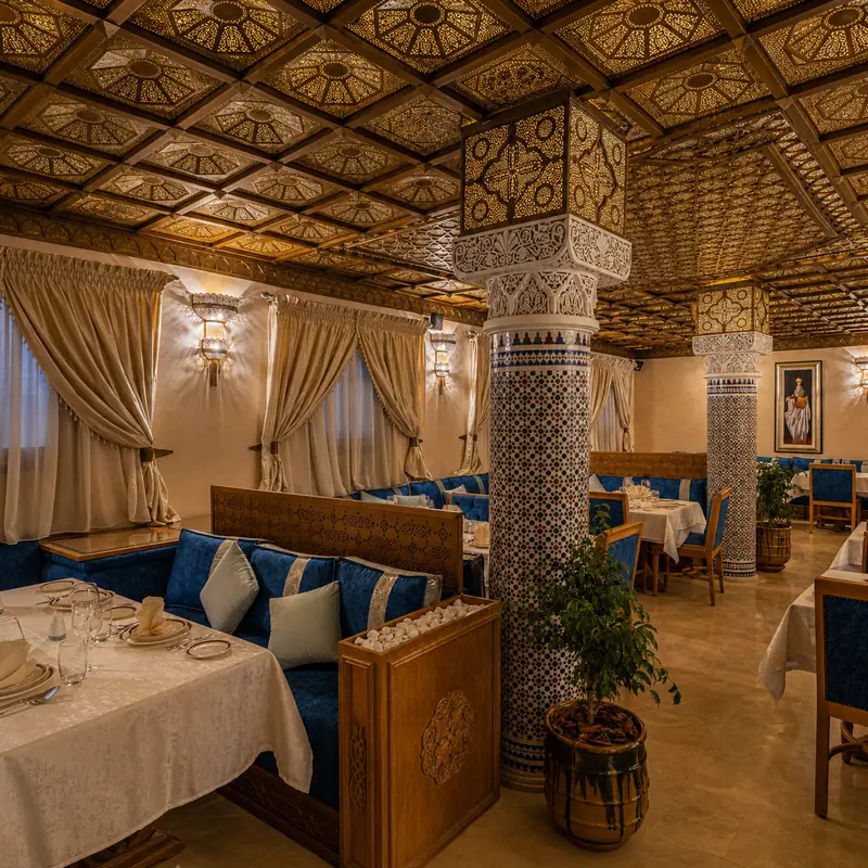 Salle de Dar El Kaid : plafond en bois sculpté, colonnes en zellige et banquettes bleues