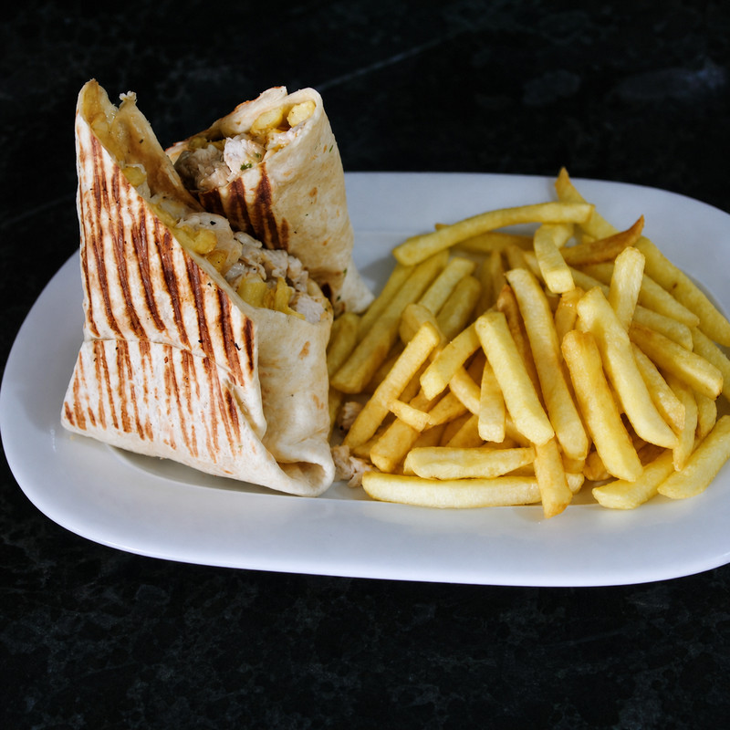 Sandwich chawarma grillé coupé en deux et frites dans une assiette blanche chez Chiche Kabab
