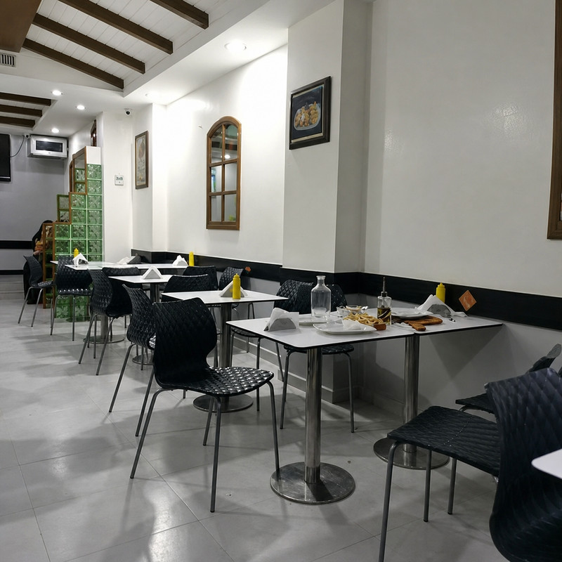 Salle de Chiche Kabab avec poutres en bois, murs blancs et chaises noires