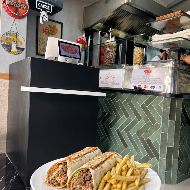 Comptoir et caisse de Chiche Kabab avec deux sandwichs chawarma et frites au premier plan