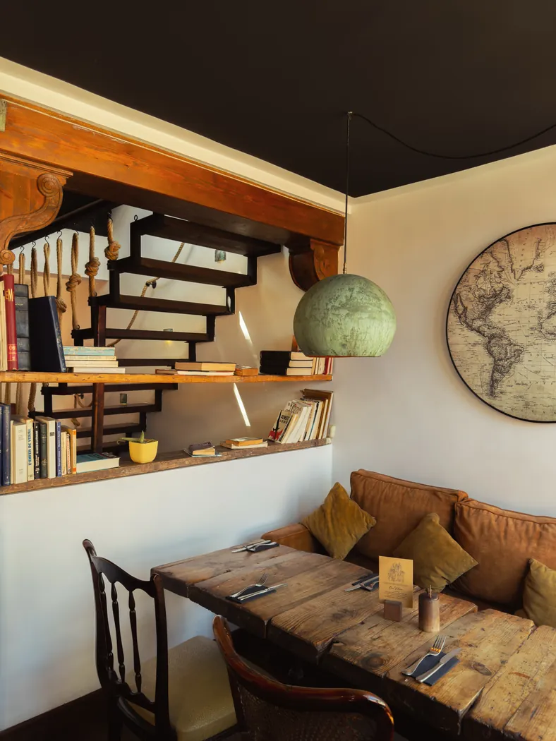 Coin salon de Mandala Society avec banquette, mappemonde et bibliothèque