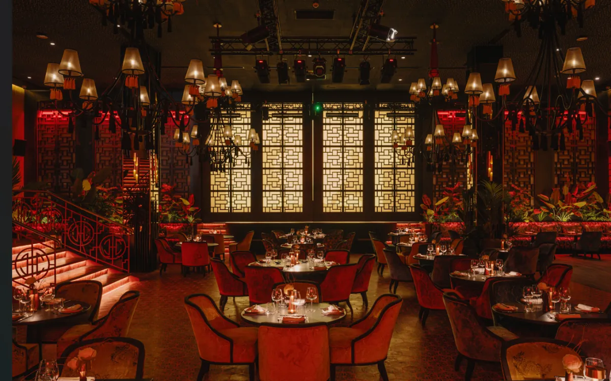 Grande salle du Buddha-Bar Agadir, lustres, claustras dorés et fauteuils rouges autour de tables rondes