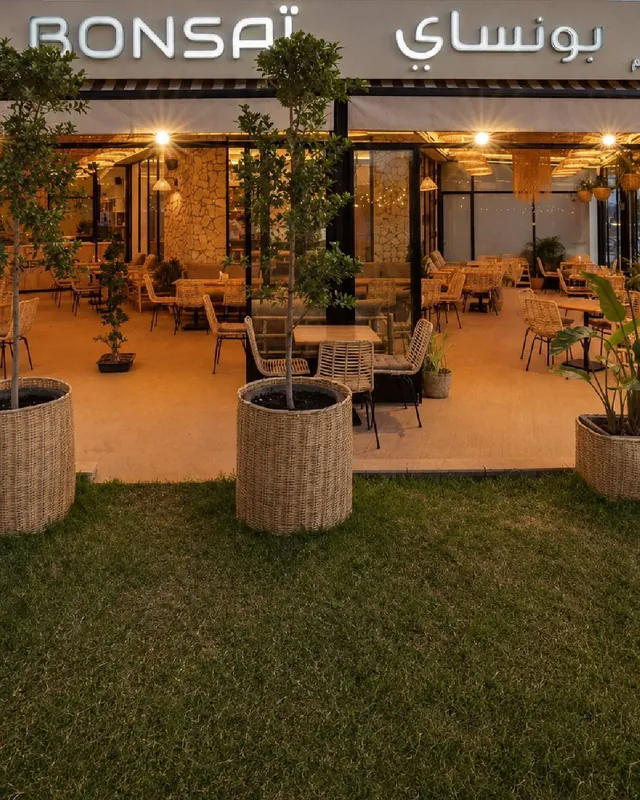 Terrasse de Bonsaï à Marrakech : pelouse, oliviers en pots et salle vitrée sous l'enseigne