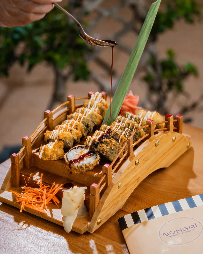 Rolls frits nappés de sauce sur un pont en bois miniature, chez Bonsaï à Marrakech