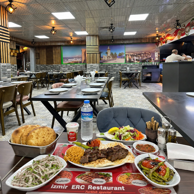 Table d'ERC Izmir avec kebab, pains turcs, mezzés et salades, grande salle en fond