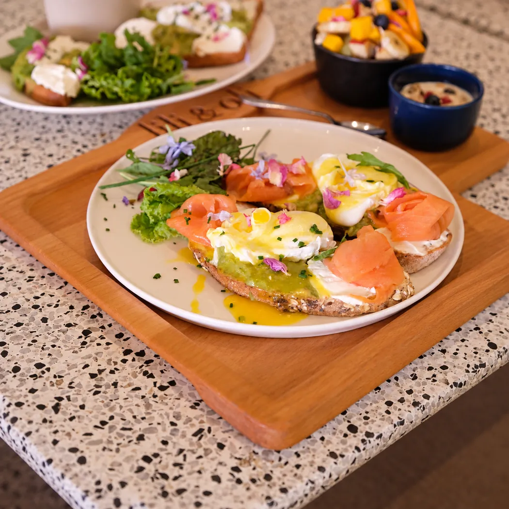 Tartines au saumon fumé et œufs pochés sauce hollandaise sur planche en bois chez Lili & Oli
