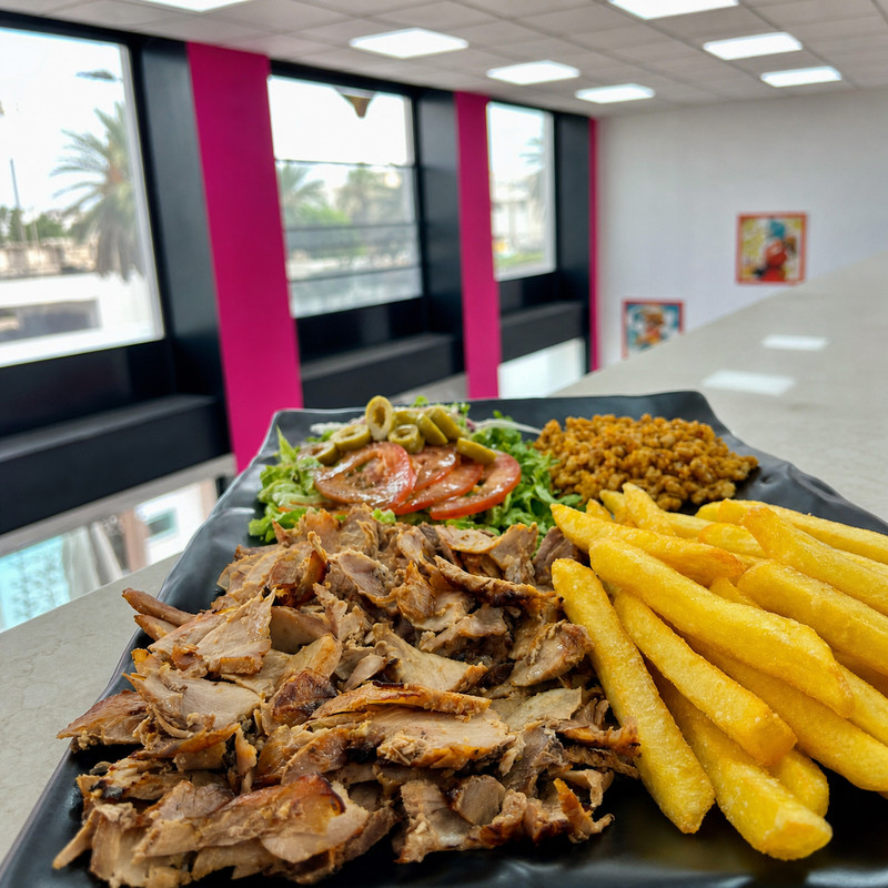 Assiette de kebab, frites, boulgour et salade devant les baies vitrées de Linan Kebab